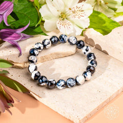 Exotic Orca Agate Bracelet of Deep Healing displayed with flowers on a natural stone background.
