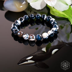 Exotic Orca Agate Bracelet of Deep Healing displayed with flowers on a natural stone background.