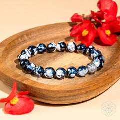 Exotic Orca Agate Bracelet of Deep Healing displayed with flowers on a natural stone background.